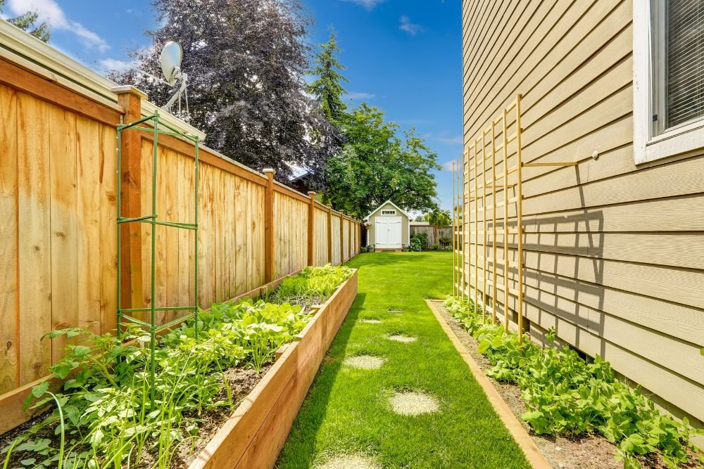 A backyard garden featuring a wooden fence surrounded by lush green grass.